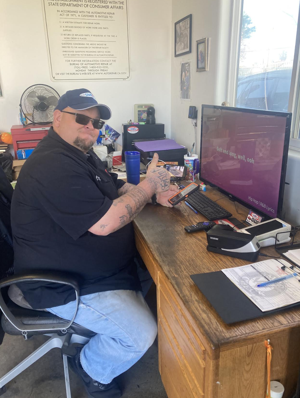 Technician at a desk beside a California Bureau of Automotive Repair sign at Upland Smog Center