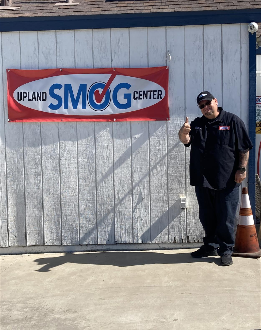 Customer Steve giving a thumbs-up in front of the Upland Smog Center banner